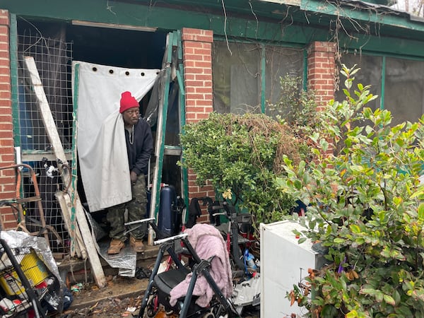 Daryl Dismukes, his wife and two others have been squatting in this vacant home on Dr. James P. Brawley Drive for a couple of years. (Bill Torpy/AJC)