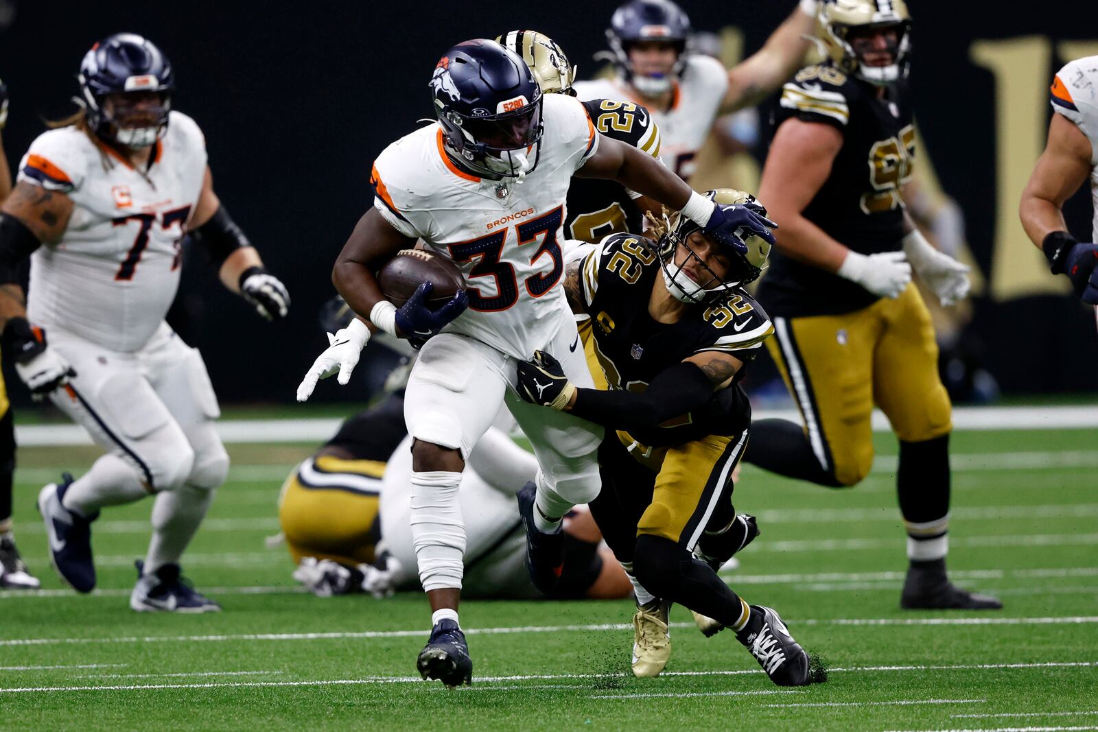 Denver Broncos running back Javonte Williams (33) breaks a tackle by New Orleans Saints safety Tyrann Mathieu (32) during the first half of an NFL football game, Thursday, Oct. 17, 2024, in New Orleans. (AP Photo/Butch Dill)