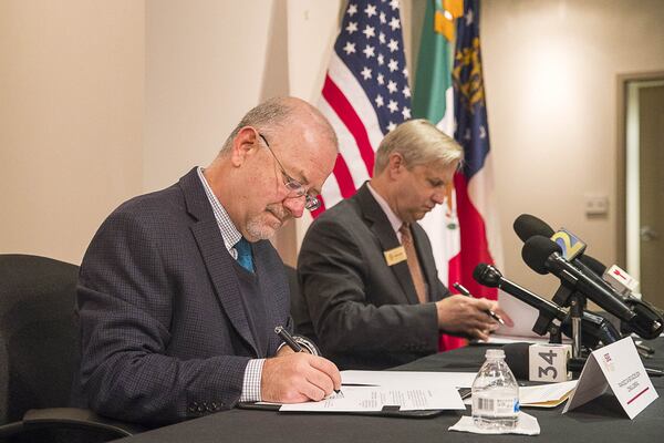 Francisco Javier Diaz De Leon (left), Consul General for Mexico in Atlanta, and Interim Director for the Division of Family and Child Services in Georgia, Tom C. Rawlings, (right) sign a memorandum of understanding regarding consular notification and access in cases involving minors during a news conference Wednesday at the Consulate General of Mexico in Atlanta. (ALYSSA POINTER/ALYSSA.POINTER@AJC.COM)