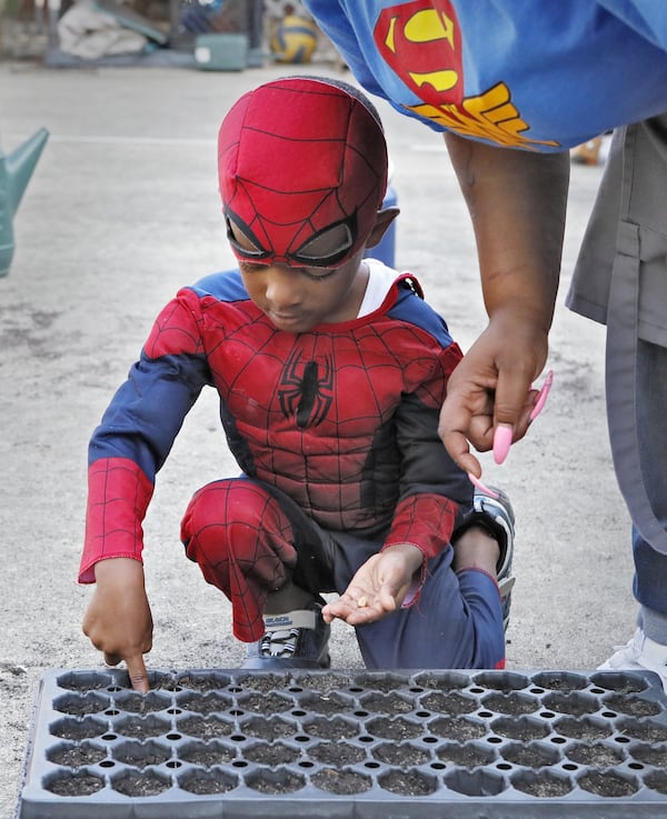 Teacher Danielle Brown helps Judah Manning, 4, plant seeds in the school garden at Little Ones Learning Center in Forest Park on Sept. 11, 2019.  