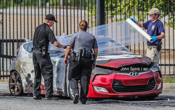 Authorities wrap up a burned car for transport to the GBI. A body was found inside the car, South Fulton police said.