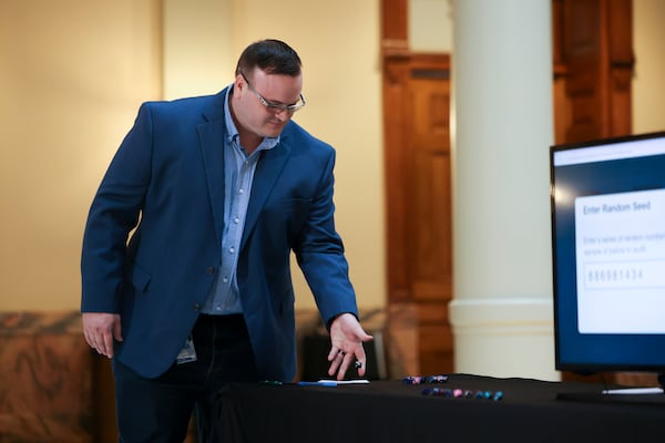 A worker in the Secretary of State’s office rolls dice during a press conference to randomly select batches of ballots to audit in the presidential election at the Georgia State Capitol, Thursday, November 14, 2024, in Atlanta. (Jason Getz / AJC)