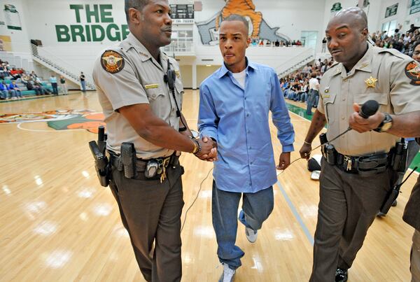 T.I. gets a warm escort from two Stockbridge High School resource officers as he leaves the gym in 2008. T.I. spoke to the students as part of his 1,000 hours of community service.