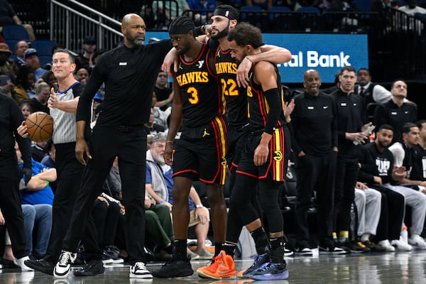 Injured Atlanta Hawks forward Larry Nance Jr. (22) is helped off of the court by guards Trae Young, right, and Caris LeVert (3) as Orlando Magic head coach Jamahl Mosley, second from left, consoles him during the second half of an NBA basketball game, Monday, Feb. 10, 2025, in Orlando, Fla. (AP Photo/Phelan M. Ebenhack)