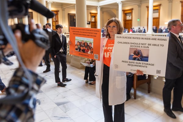 Dr. Claudia Fruin, a pediatrician, held signs advocating for gun storage laws at the Capitol in Atlanta on Monday, the first day of the legislative session.