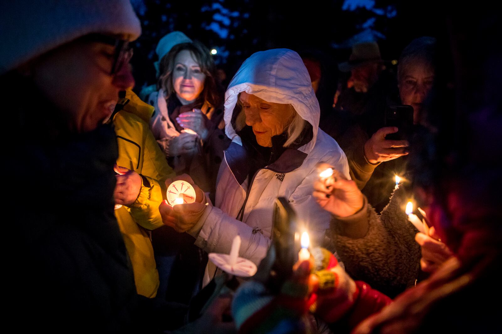 Rosalis Estes, center, keeps her candle lit in the drizzle at a vigil for grizzly bear No. 399 in Jackson, Wyo., Saturday Nov. 2, 2024. (AP Photo/Amber Baesler)