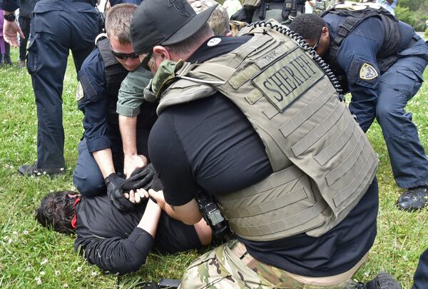 A counterprotester is held by police as the National Socialist Movement holds a rally at Greenville Street Park in downtown Newnan on Saturday, April 21, 2018. Two of the counterprotesters are now suing Coweta County and police for violating their civil rights. HYOSUB SHIN / HSHIN@AJC.COM