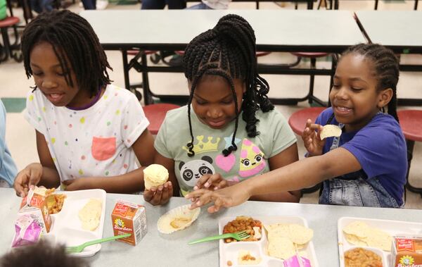 Aubrey Harris, left, Lauren Emanuel and Arianna Jordan, second grade students, eat lunch at Burgess-Peterson Academy in Atlanta on Friday. To celebrate Earth Day, Burgess-Peterson Academy is one of about 15 Atlanta schools that used biodegradable products, such as trays and forks. EMILY HANEY / emily.haney@ajc.com