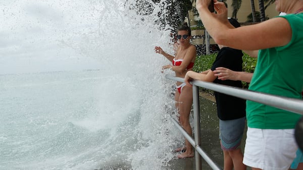 Elizabeth Dragan is splashed by a wave on a walkway along Waikiki Beach ahead of Hurricane Lane, Friday, Aug. 24, 2018, in Honolulu.