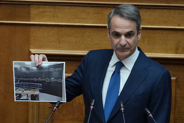 Greek Prime Minister Kyriakos Mitsotakis holds up a photograph of a new railway control facility during his speech in parliament, ahead of the submission of a no-confidence motion by opposition parties over the government's handling of Greece's worst rail disaster two year ago, in Athens, Wednesday, March 5, 2025. (AP Photo/Thanassis Stavrakis)