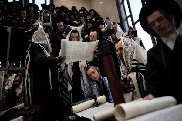 Jewish ultra-Orthodox men and children, some wearing costumes read the Book of Esther, which tells the story of the Jewish festival of Purim, at a synagogue in Bnei Brak, Israel, Friday, March 14, 2025. (AP Photo/Oded Balilty)