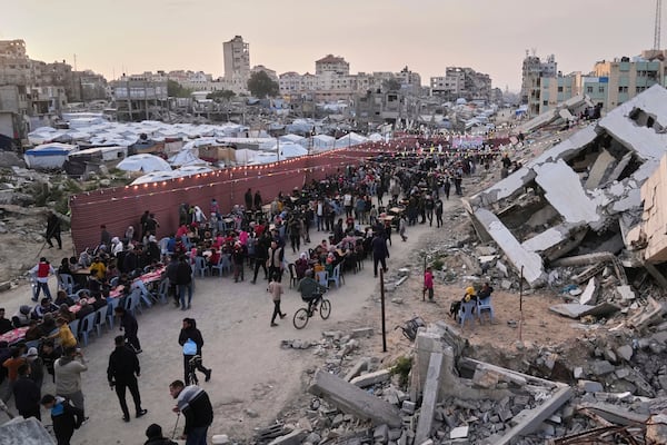 Palestinians sit at a large table surrounded by the rubble of destroyed homes and buildings as they gather for iftar, the fast-breaking meal, during Ramadan in Gaza City, Thursday March 6, 2025 (AP Photo/Abdel Kareem Hana)