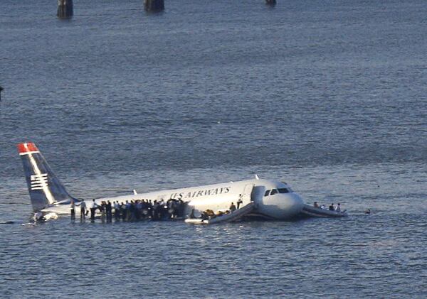 Passengers stand on the wings of a U.S. Airways plane as a ferry pulls up to it after it landed in the Hudson River in New York, January 15, 2009. REUTERS/Brendan McDermid