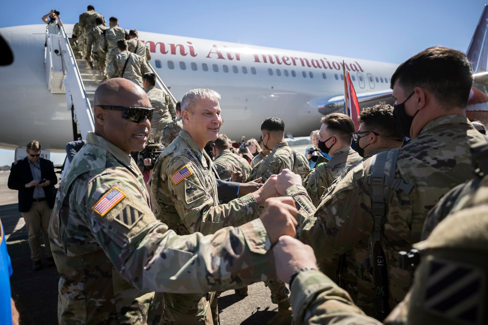 SAVANNAH, GA - MARCH 2, 2022: Command Sergeant Major Quentin Fenderson, center, and Major General Charles Costanza fist bump soldiers with the U.S. Army 3rd Infantry Division, 1st Armored Brigade Combat Team as they board an airplane at Hunter Army Airfield during their deployment to Germany, Wednesday Mar. 2, 2022 in Savannah, Ga. (AJC Photo/Stephen B. Morton)