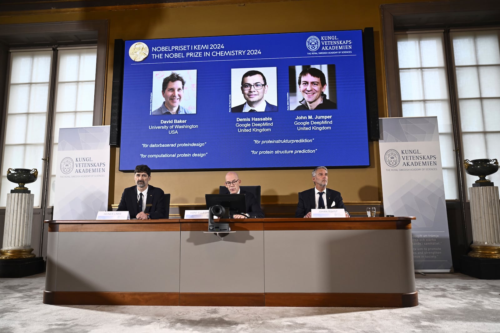 Johan Åqvist, member of the Nobel Committee for Chemistry, Hans Ellegren, Permanent Secretary and Heiner Linke, Chairman of the Nobel Committee for Chemistry award this years Nobel Prize in Chemistry to David Baker, Demis Hassabis, and John M Jumper at the Royal Swedish Academy of Sciences, in Stockholm, Sweden, Wednesday, Oct. 9, 2024. (Christine Olsson/TT News Agency via AP)