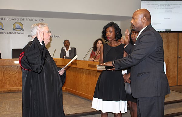 Rockdale County Public Schools Superintendent Terry Oatts (right) – accompanied by his, wife Yolanda (center), daughter Teryn, and son Landon (obscured) – is sworn in by Rockdale County Superior Court Judge Robert Mumford. The ceremony was held during the May 30, 2020, special called meeting by the Rockdale County Board of Education and attended by community members, elected officials and public schools employees. AJC file 2020