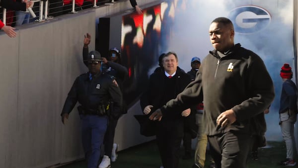 UGA football staff member Bryant Gantt leads the team onto the field at Sanford Stadium in Athens during a January 14 championship celebration. Gantt, the program's director of player support and operations, has job duties that include acting as the team's liaison to law enforcement. Gantt grew up in Athens and was a player who lettered on the team in 1989 and 1990. (Ryon Horne/Ryon.Horne@ajc.com)