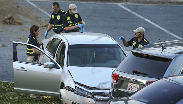 GBI agents examine the car in which Deravis Caine Rogers was shot and killed by Atlanta police June 22 as he drove off. Atlanta police fired the officer July 1 for excessive use of force. John Spink / jspink@ajc.com