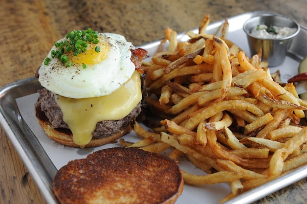 The Burger at Two Birds Taphouse with dry-aged, pasture-raised beef, Gouda, bacon, charred sweet onion, smoked mushroom on a brioche bun with a side of fries. You can add an egg to it, too. (BECKY STEIN PHOTOGRAPHY)