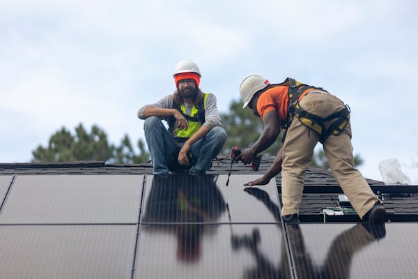 Joe McClain, left, and Mike Harris, right, installers for Creative Solar USA, install solar panels on a home in Ball Ground, Georgia on December 17th, 2021. (Nathan Posner for The Atlanta Journal-Constitution)