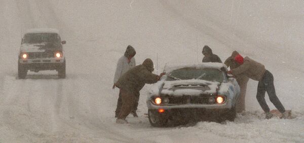 This photo from the blizzard of '93 (which happened in March) shows good samaritans lending a hand to a stuck motorist at the intersection of Cheshire Bridge Road and Lenox Road. (DAVID TULIS/STAFF)