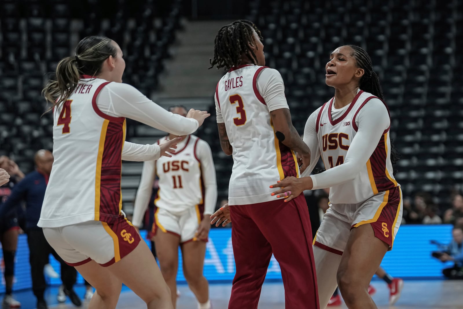 USC Trojans's forward Kiki Iriafen, right, celebrates the victory with guard Aaliyah Gayles, centre, and guard Rian Forestier during the basketball match between the University of Southern California (USC) and Ole Miss, Monday, Nov. 4, 2024 in Paris, France. (AP Photo/Aurelien Morissard)