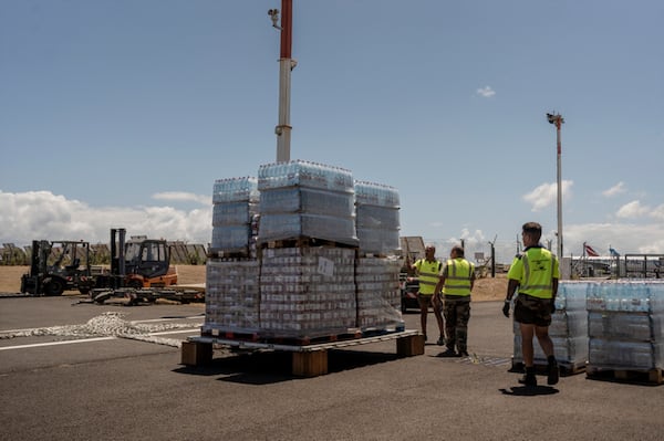 French civil security personnel load pallets of water on a transport plane for Mayotte from Saint Denis on Reunion Island, Tuesday, Dec. 17, 2024. (AP Photo/Adrienne Surprenant)