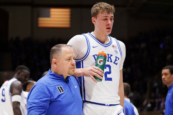 Duke's Cooper Flagg (2) walks off the court with head athletic trainer Jose Fonseca, left, after being accidentally hit in the face in the first half of an NCAA college basketball game against Florida State in Durham, N.C., Saturday, Mar. 1, 2025. (AP Photo/Ben McKeown)