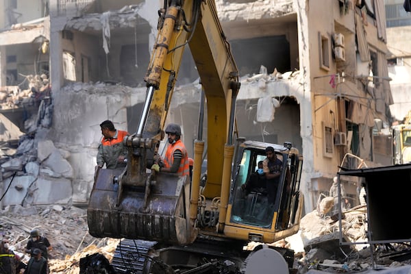 Rescue workers stand on an excavator as they search for victims at the site of an Israeli airstrike that hit central Beirut, Lebanon, Saturday, Nov. 23, 2024. (AP Photo/Hussein Malla)