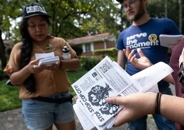 Eva Cardenas (left) Seth Roseman and Shehza Anjum huddle while canvasing neighborhoods in opposition of the proposed police and fire training center.  Ben Gray for the Atlanta Journal-Constitution