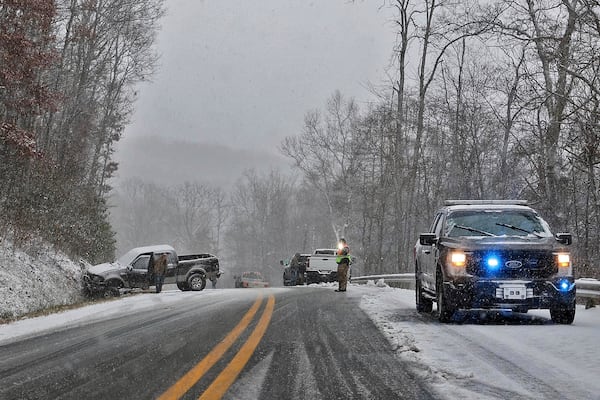 A driver, left, waits for his truck to be removed from an accident site after sliding into a hillside during snow showers, Thursday, Nov. 21, 2024, near Quinwood, W.Va. (Jenny Harnish/The Register-Herald via AP)