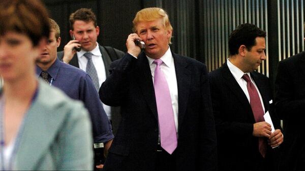 In this Sept. 14, 2005 photo, businessman Donald Trump talks on his cell phone outside after speaking at the Bixpo 2005 business convention at the Budweiser Events Center in Loveland, Colo. On the right, is Felix Sater. A lawsuit has accused the Russia-born businessman, Sater, with ties to President Trump of hacking a Hollywood friend's electronics and accessing confidential information about her celebrity clients. Sater denied those allegations Monday, March 4, 2019, telling The Associated Press they had absolutely no truth to them.  