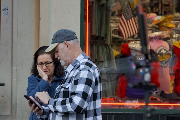 People react at the intersection of Bourbon Street and Canal Street during the investigation after a pickup truck rammed into a crowd of revelers early on New Year's Day, Wednesday, Jan. 1, 2025, in New Orleans. (AP Photo/Matthew Hinton)