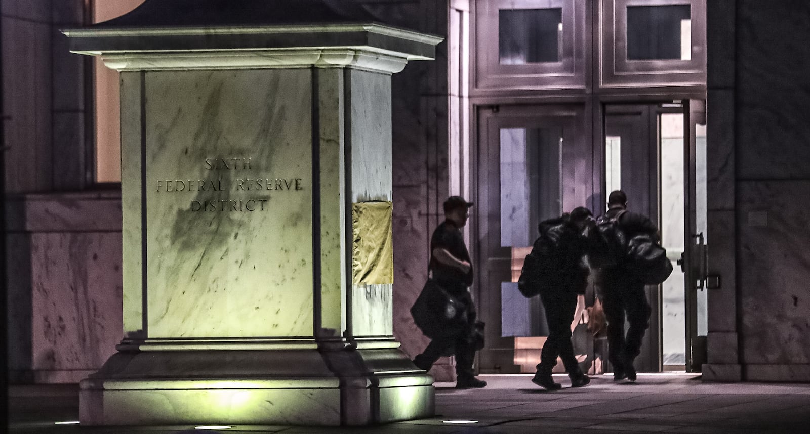 One side of a stone marker at the Federal Reserve Bank of Atlanta was scrubbed clean of graffiti on Friday morning, while the other was covered by paper during an investigation into overnight vandalism at the federal building and the nearby rainbow crosswalk in Midtown Atlanta.