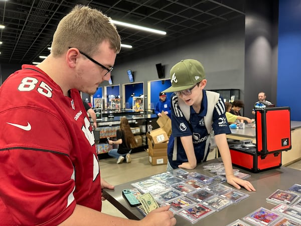 During  trade night at CardsHQ, 22-year-old Dylan Gravel and 10-year-old Cade Light barter cards. RODNEY HO/rho@ajc.com