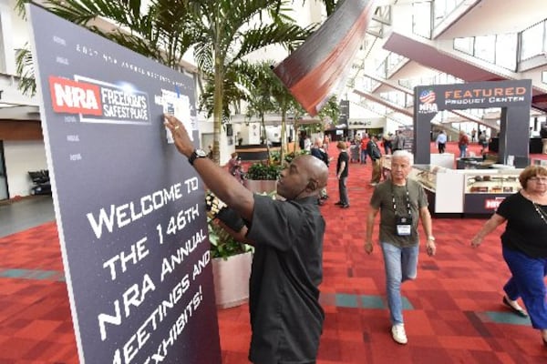 Donovan Holtzclaw sets up a banner at the Georgia World Congress Center in preparation for the NRA convention. HYOSUB SHIN / HSHIN@AJC.COM