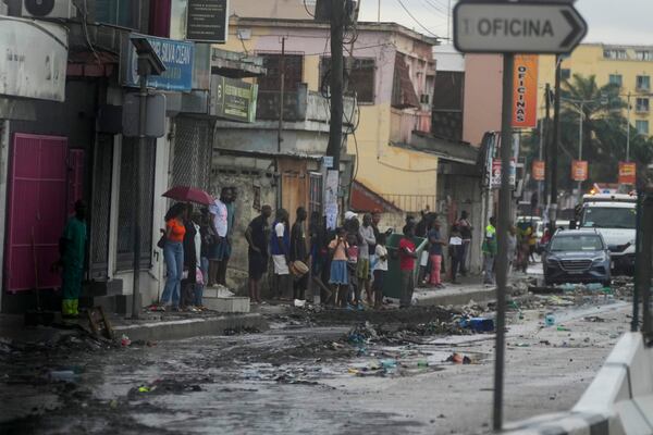 People watch President Joe Biden's motorcade drive through Luanda, Angola, Tuesday, Dec. 3, 2024. (AP Photo/Ben Curtis)