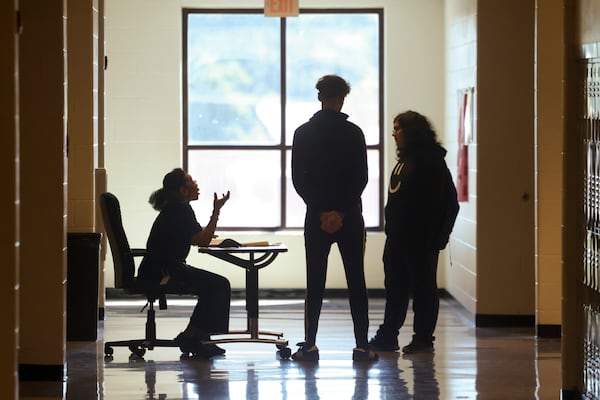 Assistant Principal Angel Rivers, sitting at her desk, talks with campus monitor Jacob Rolon, center, and a student in the hallway at South Gwinnett High School, Friday, March 29, 2024, in Snellville, Ga. Principal Rodney Jordan (not pictured) has implemented campus monitors, assistant principals and other staff members to be position in various portions of the school to monitor the hallways for all transitions. Principal Jordan purchased 12 desks to implement the strategy. (Jason Getz / jason.getz@ajc.com)