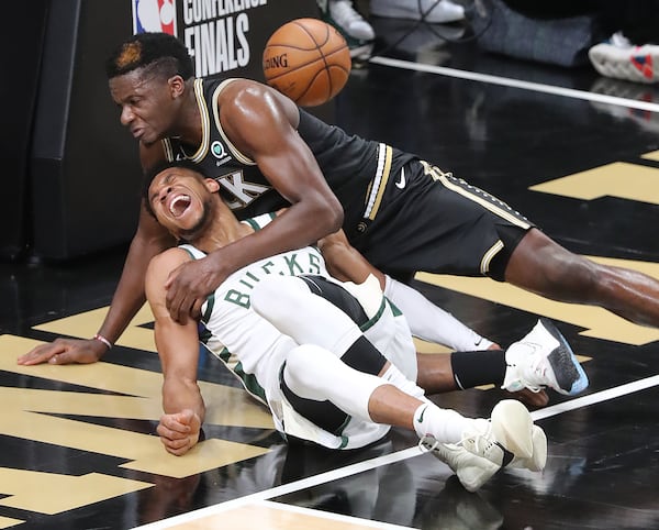 Hawks center Clint Capela and Milwaukee Bucks forward Giannis Antetokounmpo fall to the hardwood after battling at the basket during the third quarter of Game 4 of the Eastern Conference finals Tuesday, June 29, 2021, at State Farm Arena in Atlanta. Antetokounmpo left the game with an apparent knee injury. (Curtis Compton / Curtis.Compton@ajc.com)