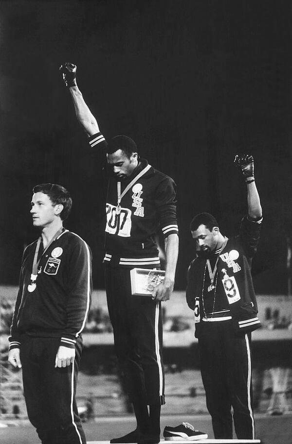 Extending gloved hands skyward in racial protest, U.S. athletes  John Carlos, right, and Tommie Smith, center, made a statement during the medal awards ceremony for 200-meter run at the 1968 Olympics in Mexico City.