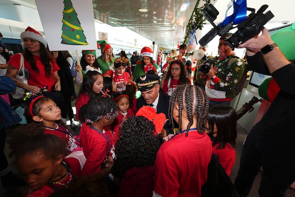 Captain Paul Purkey, center, pins wings on participants during the United Airlines annual "fantasy flight" to a fictional North Pole at Denver International Airport, Saturday, Dec. 14, 2024, in Denver. (AP Photo/David Zalubowski)