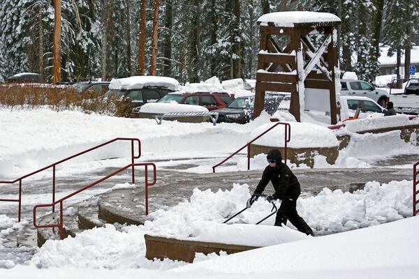 A worker scoops snow from a sidewalk during a storm Thursday, Nov. 21, 2024, at Sugar Bowl Ski Resort in Norden, Calif. (AP Photo/Brooke Hess-Homeier)