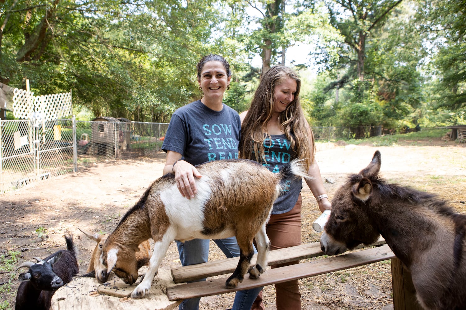 Judy Byler (left), founder and CEO of Our Giving Garden, and Hillary Jensen, director of Our Giving Garden, try to rally the farm animals for a photo on Wednesday, June 7, 2023, in Mableton, Georgia. Our Giving Garden is a nonprofit community garden that donates fresh produce to families without access to it. CHRISTINA MATACOTTA FOR THE ATLANTA JOURNAL-CONSTITUTION.