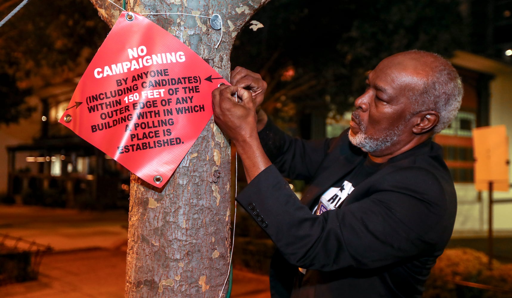 October 17, 2022 Atlanta: Poll worker Dacosta Jordan readies the outside of the precinct with signs. Several dozen voters were there in the first hour of early voting at the Buckhead Library located at 269 Buckhead Avenue NE in Atlanta on Monday, Oct. 17, 2022.(John Spink / John.Spink@ajc.com) 

