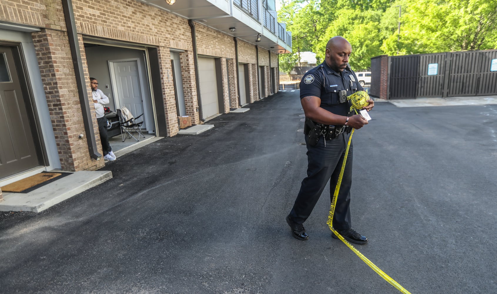 A man watches from the residence where family and friends of the victim gathered at the One Riverside West complex. A police officer winds up crime scene tape.