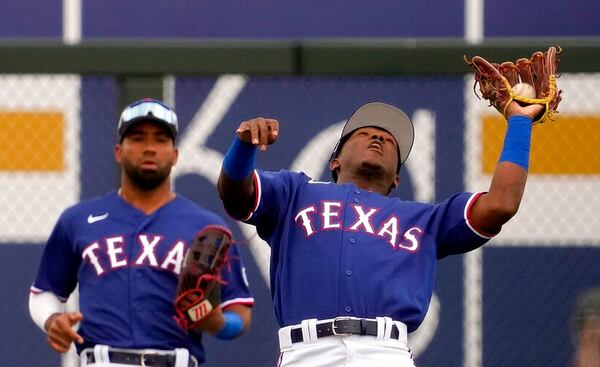 Texas Rangers shortstop Luisangel Acuna, right, catches a fly ball for the out on Colorado Rockies' Elehuris Montero during the fifth inning of a spring training baseball game Tuesday, Feb. 28, 2023, in Surprise, Ariz. (AP Photo/Charlie Riedel)