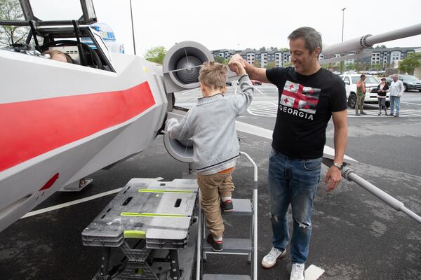 Dr. Akaki Lekiachilli helps Artimy Osadchiy, 5, onto his near life-like replica of an X-Wing Starfighter from Star Wars at Embry Village shopping center on Chamblee Tucker Road Saturday, April 16, 2022. (Steve Schaefer / steve.schaefer@ajc.com)