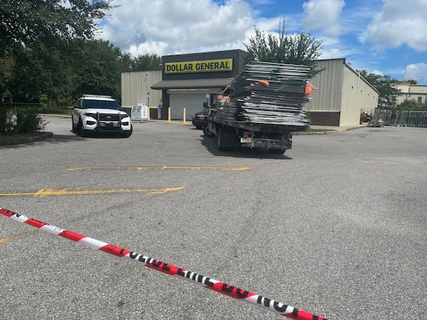 A police vehicle and truck carrying portable fencing sit in the parking lot of a Dollar General store Monday in Jacksonville, where three people were killed by a gunman in a racially motivated attack on Saturday afternoon.