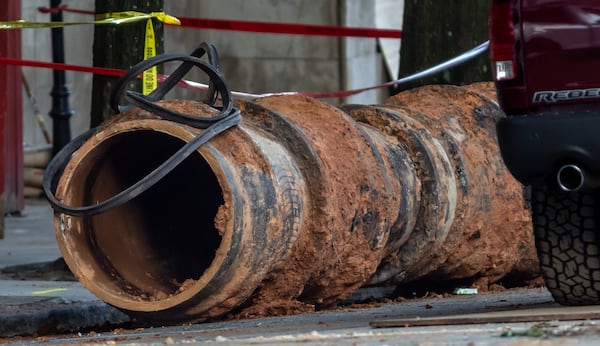 Here one of the pipes removed from the hole is set aside on the street while a large 30-inch pipe was seen being lowered into the hole at 11th and West Peachtree Street Tuesday morning, June 4, 2024. According to the city, the Department of Watershed Management was ready to start installing and conducting the remaining steps to restore water service. (John Spink/AJC)