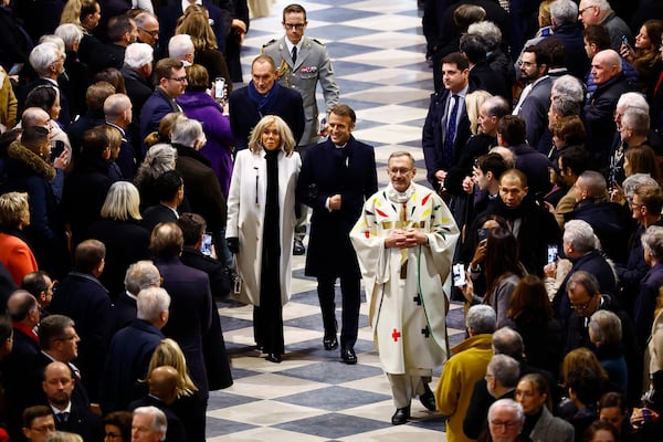 FILE - French President Emmanuel Macron, center, and his wife Brigitte Macron arrive to attend the inaugural Mass, with the consecration of the altar, at the Notre Dame Cathedral, five-and-a-half years after a fire ravaged the Gothic masterpiece, as part of ceremonies to mark the Cathedral's reopening after its restoration, in Paris, France, Sunday, Dec. 8, 2024. (Sarah Meyssonnier/Pool Photo via AP)